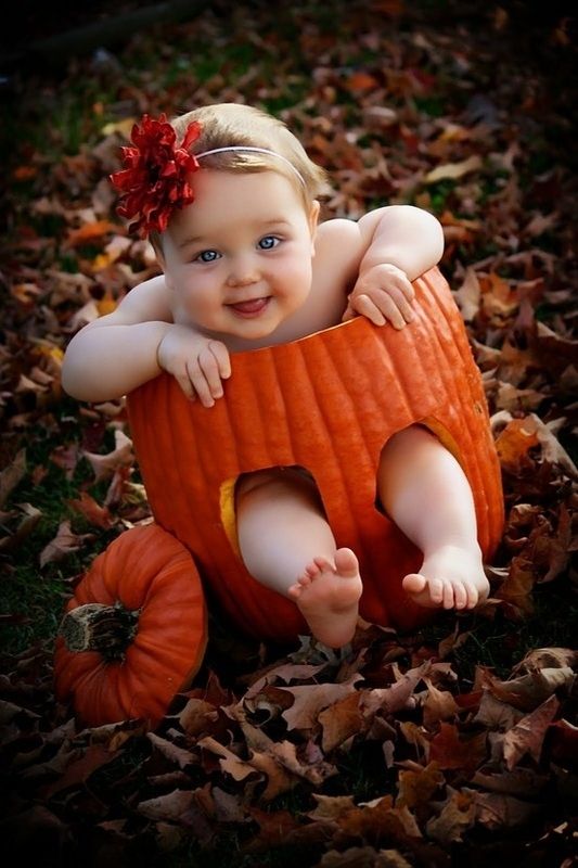 image of a baby sitting in a funny pumpkin
