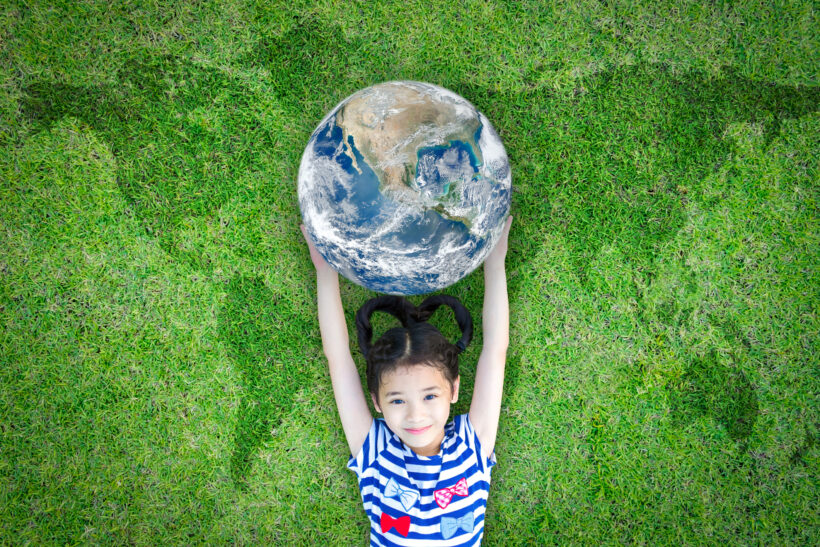 Earth day, ecological friendly and corporate social responsibility concept with kid raising world on green lawn: Element of the image furnished by NASA