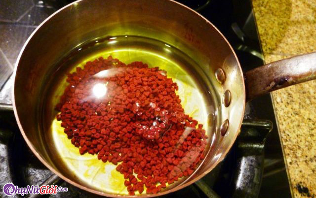 Đun nóng dầu ăn rồi cho hạt điều đỏ vào khuấy đều