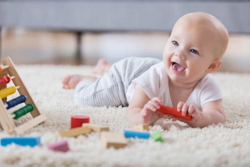 Cute baby sings with open mouth while playing with wooden blocks