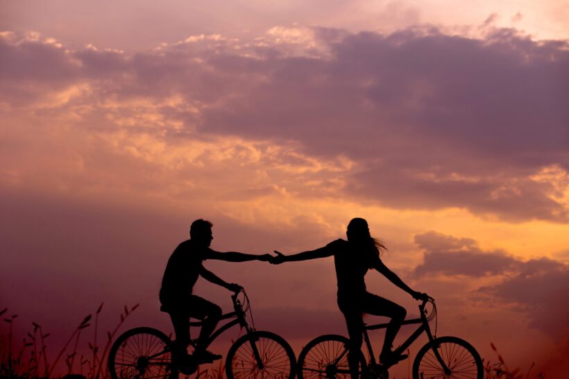 hình nắm tay đạp xe trong ánh chiều buông xuống lãng mạn